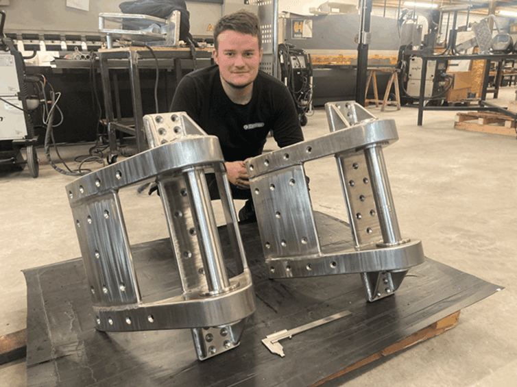 Salarié de Celtinox dans l'atelier derrière deux berceaux mécano-soudés en aluminium